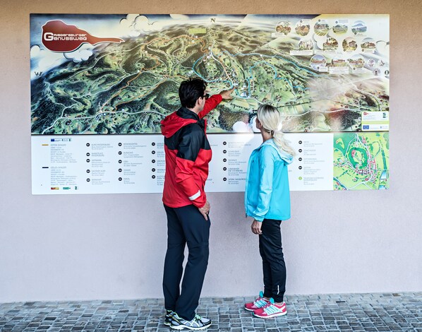 A large map with a red and black jacketed person pointing at it.