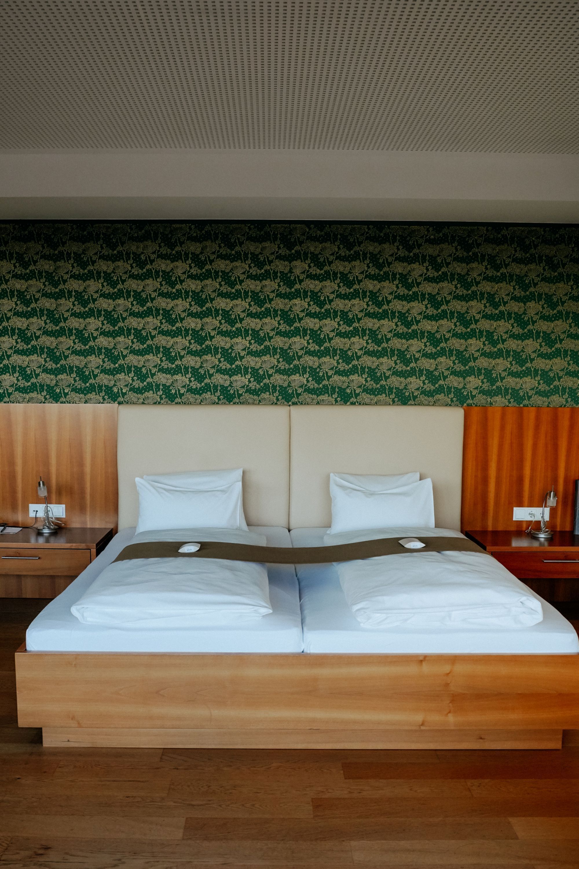 A double bed with a wooden frame, two pillows, and a brown blanket.