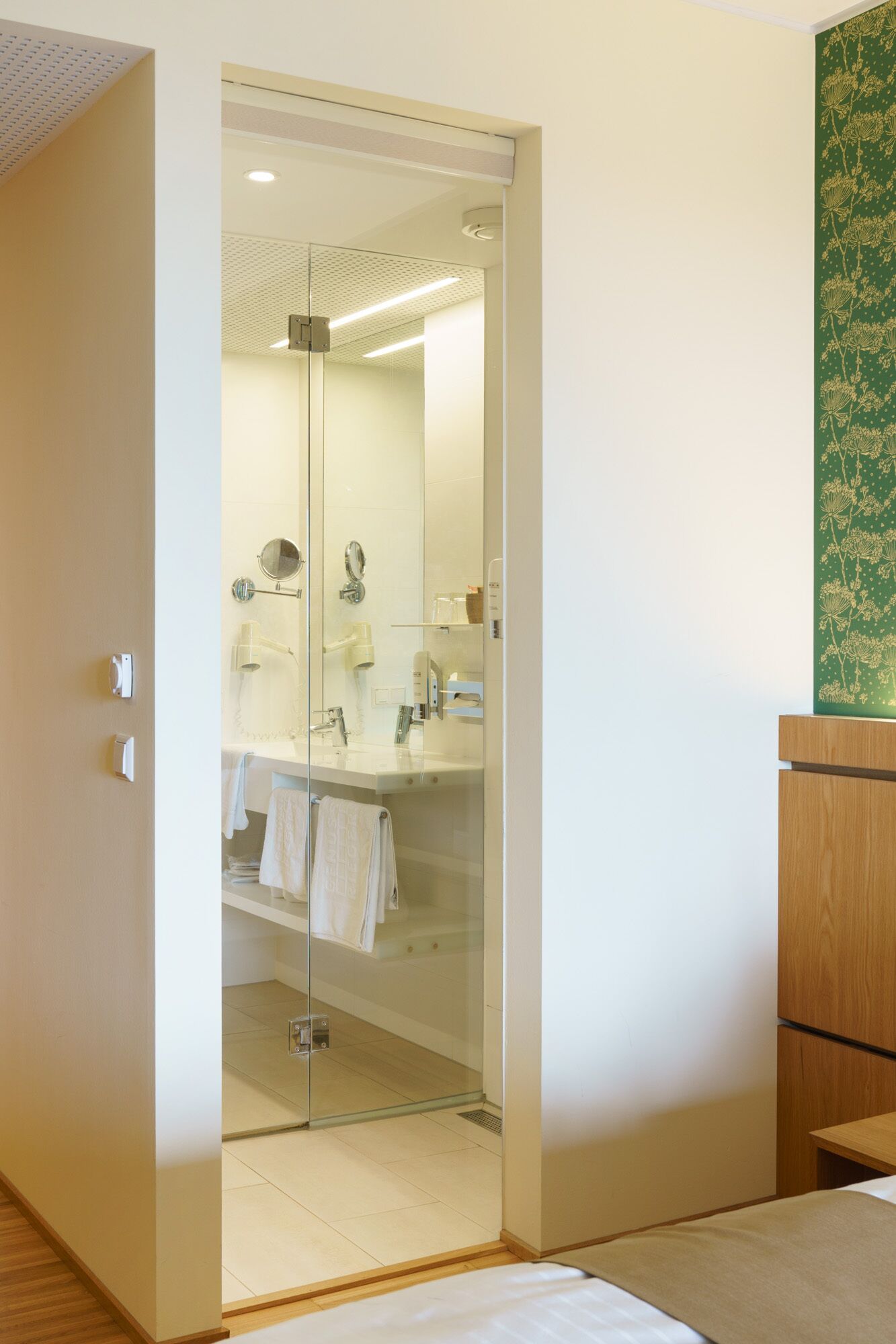 A modern bathroom with a glass-enclosed shower, a white sink, and a mirror.