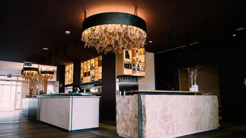 A bar area with a central island, shelves with bottles, and hanging floral decorations.