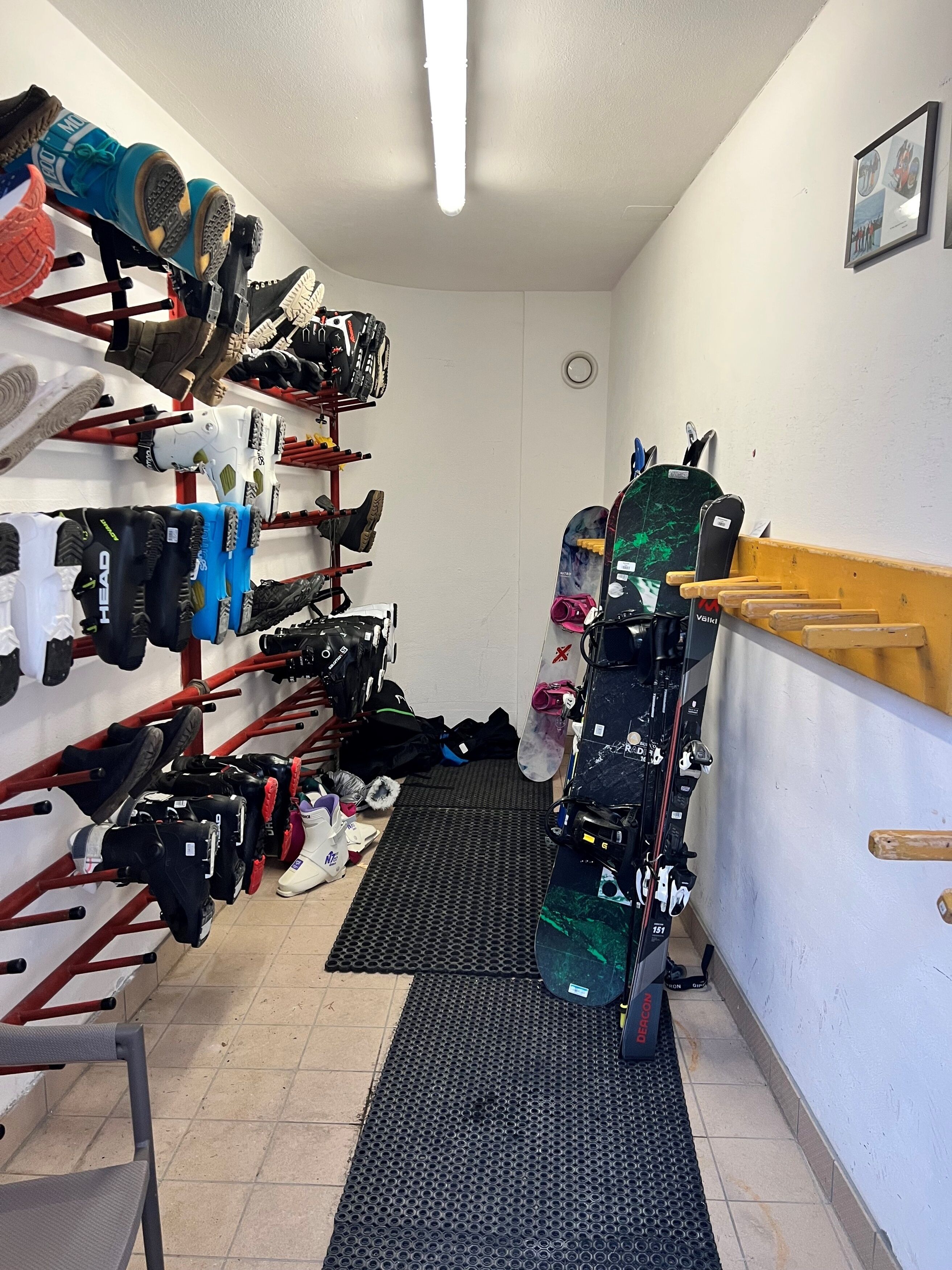 Un almacén con estantes llenos de calzado diverso y una tabla de snowboard apoyada en la pared.