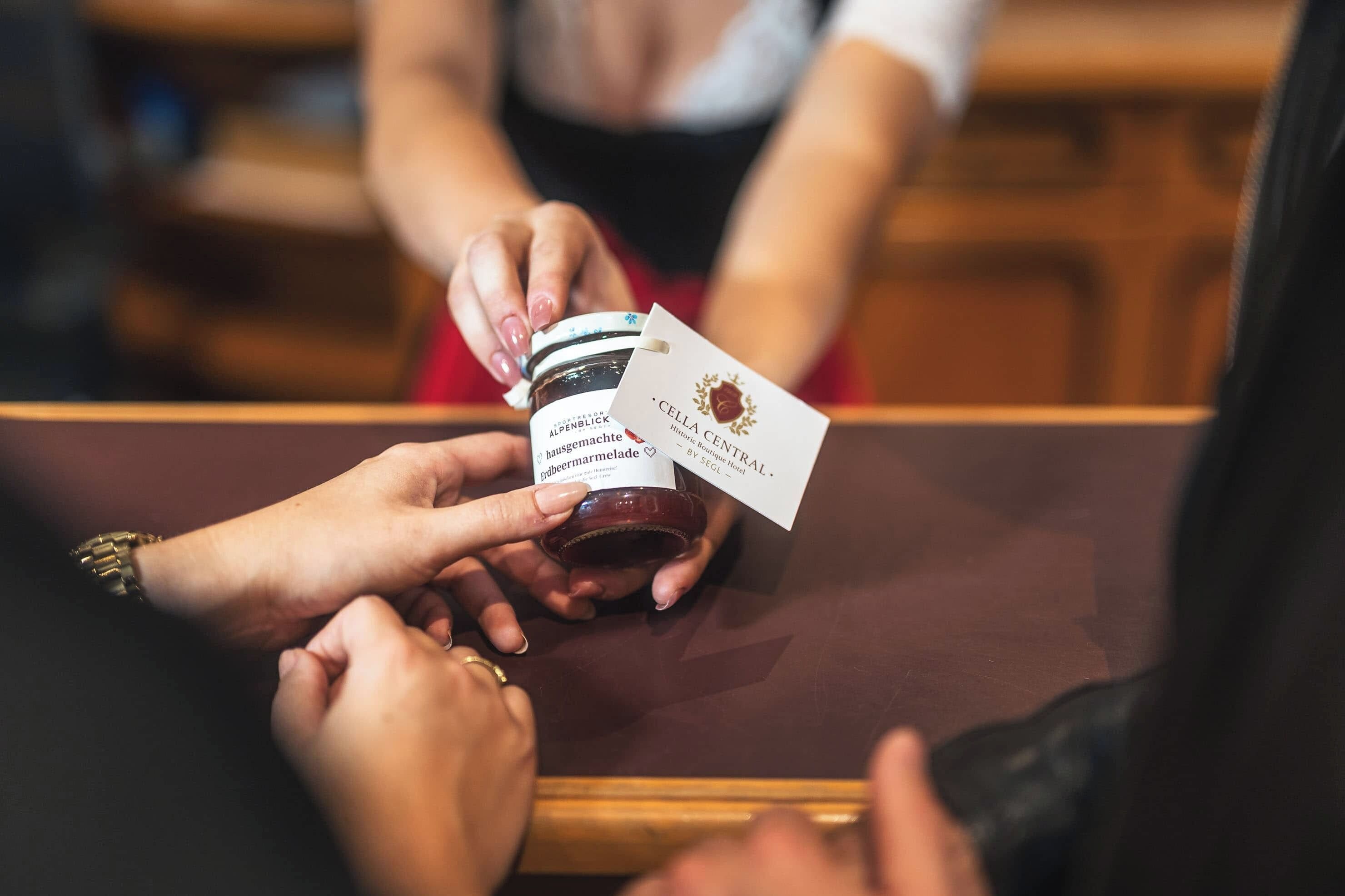 A person holding a jar of jam with a label and a card.