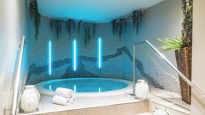 Ein moderner Wellnessbereich mit Whirlpool, Zierpflanzen und einer Steinwand.