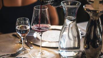 A table with wine glasses, a water pitcher, and a bottle of wine being poured.
