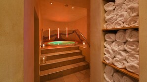Ein Wellnessbereich mit Whirlpool, Treppe und Handtuchablagen.