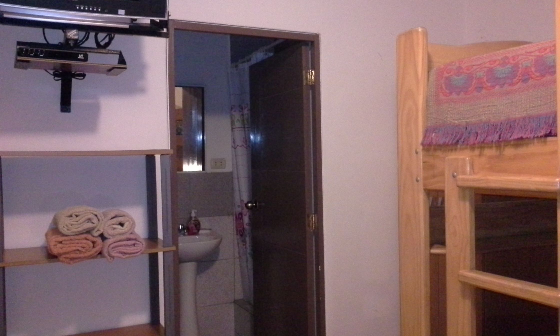 Un baño con un estante de madera que sostiene toallas, un espejo y un lavabo.