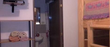 Un baño con un estante de madera que sostiene toallas, un espejo y un lavabo.