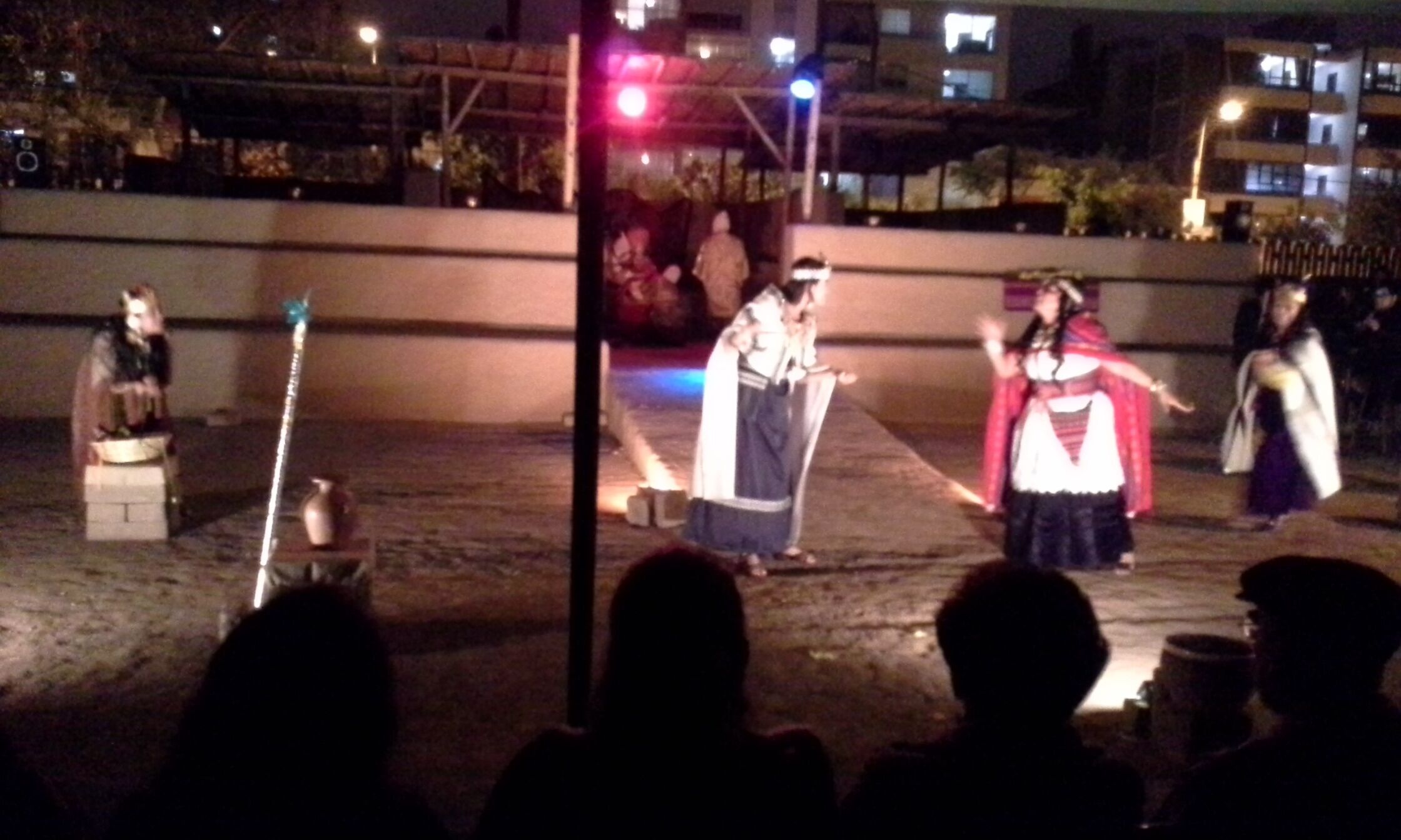 Una presentación nocturna al aire libre con actores vestidos con trajes tradicionales.