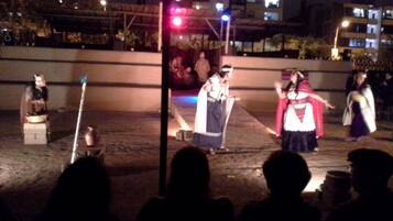 Una presentación nocturna al aire libre con actores vestidos con trajes tradicionales.
