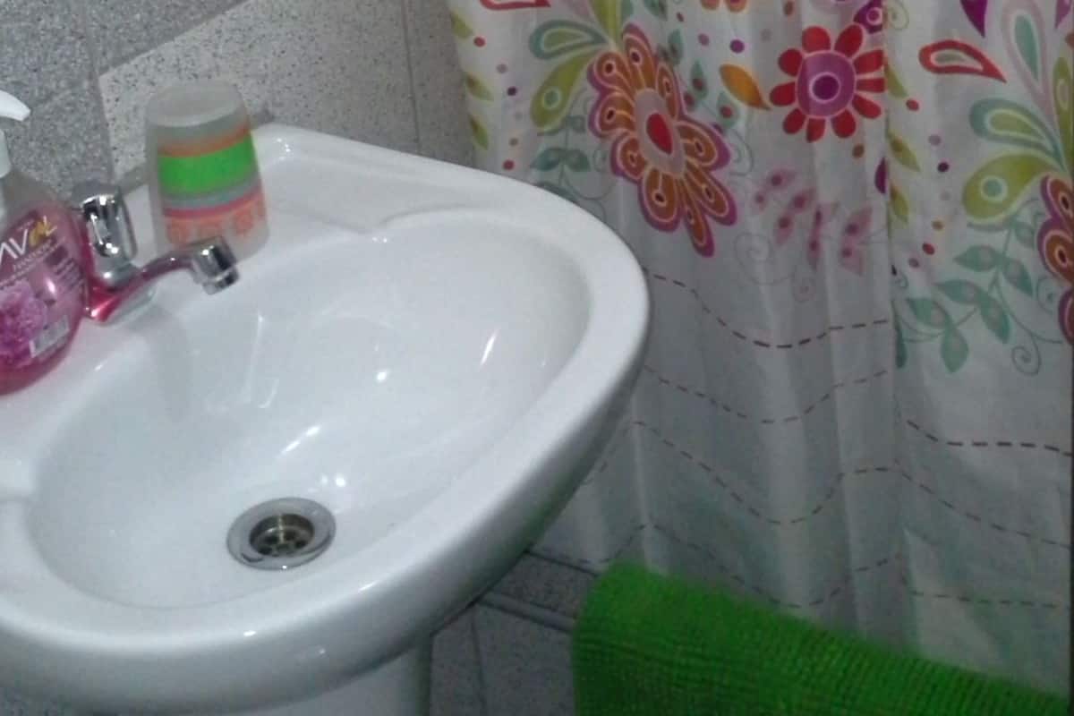 A bathroom with a white sink, a green towel, and a floral shower curtain.
