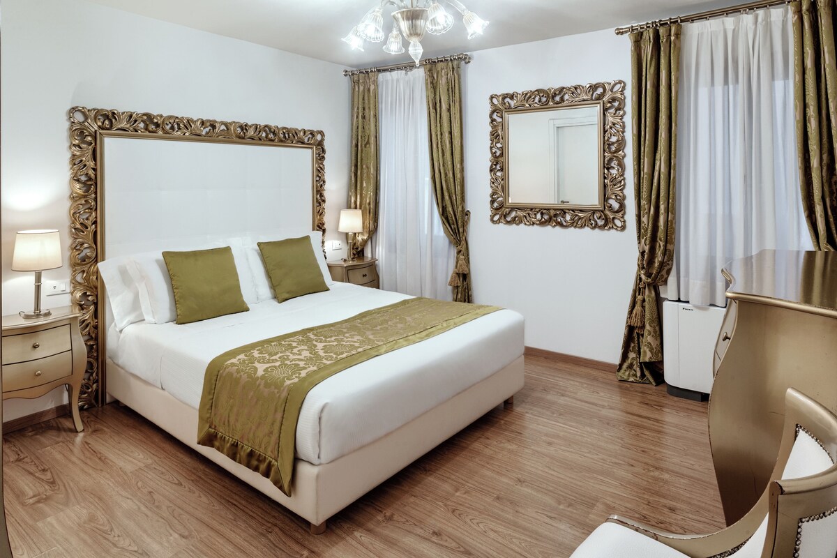 A hotel room with a large bed, two bedside tables, a desk, and a chair.