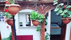 Un balcón de madera con macetas colgantes, un sofá rojo y una cama al fondo.