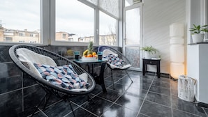 Ein Balkon mit Korbstühlen, einem Tisch mit Früchten und einer Topfpflanze.