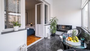 Ein Balkon mit Esstisch, Blumentöpfen und Obstschale.