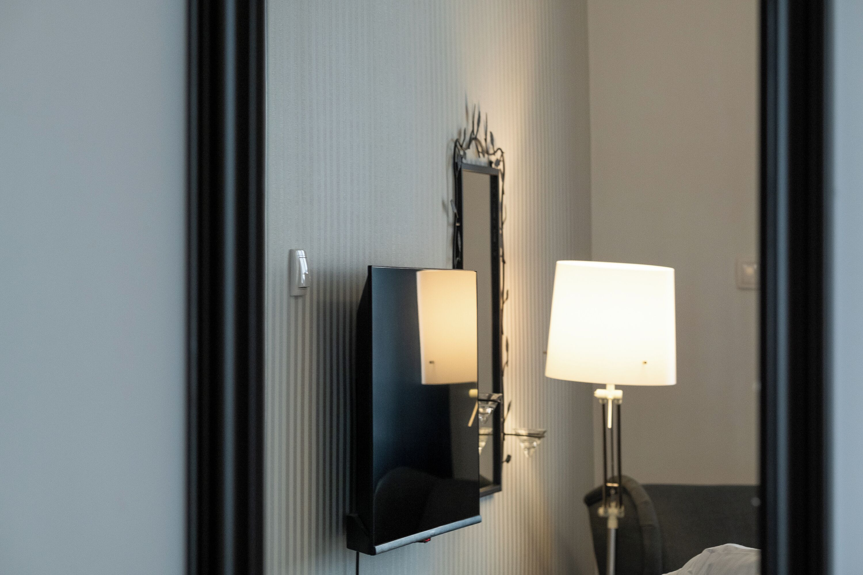 Une salle de bain avec un miroir, un luminaire fixé au mur et un lampadaire.