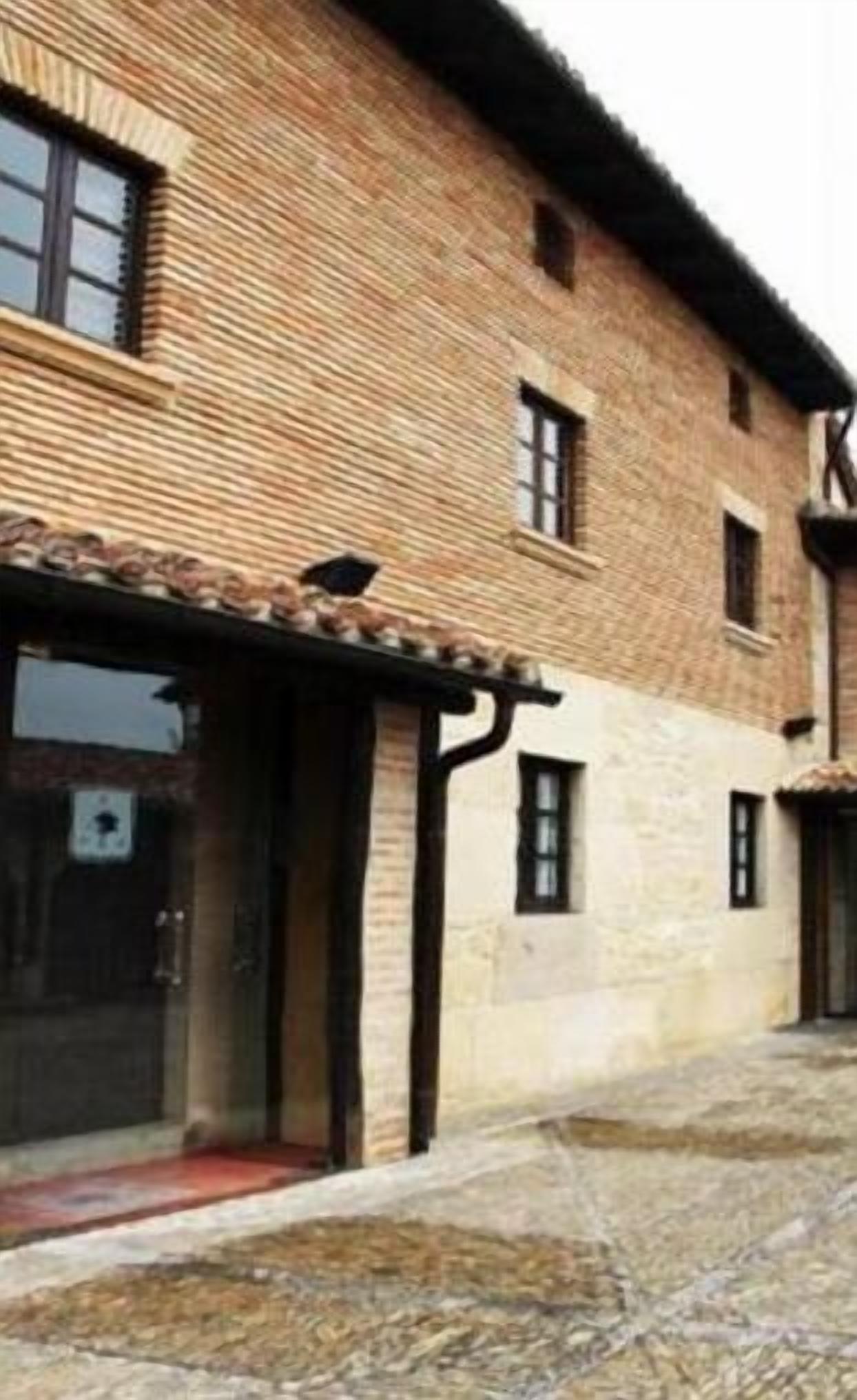 A traditional brick building with a tiled roof, a covered entrance, and a courtyard.