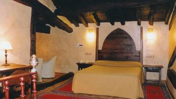 A traditional room with a bed, a nightstand, a lamp, and a red carpet.