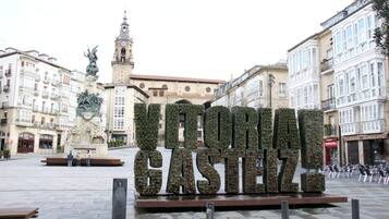 A public square with a large sign reading "VITORIA GASTEIZ".