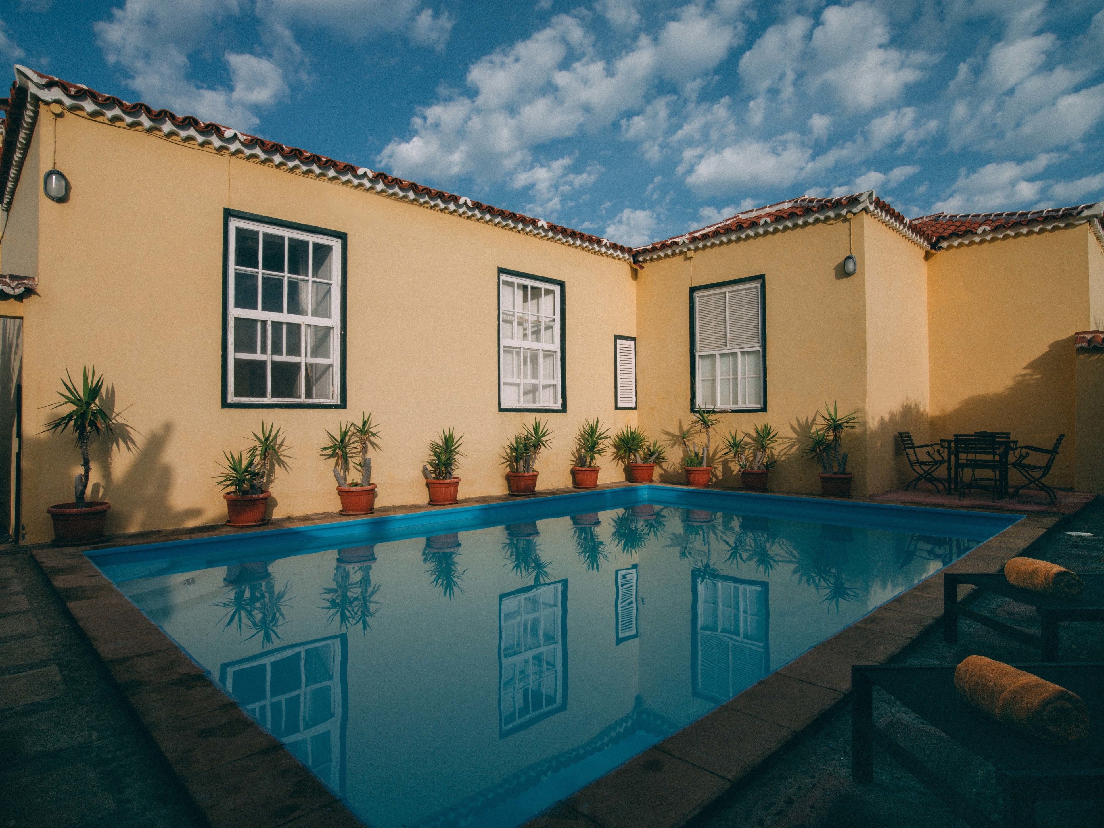 Une piscine dotée d’une terrasse carrelée, de plantes en pot et de mobilier d’extérieur.