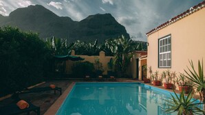 A swimming pool with a tiled edge, surrounded by potted plants and outdoor furniture. - Hotel Rural Casamarilla (Garachico)