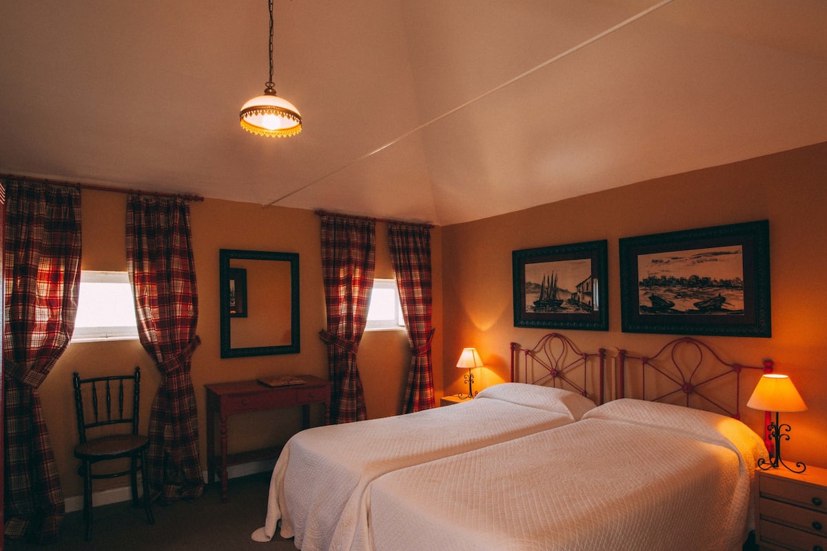 A bedroom with two beds, a desk, a chair, and two lamps.
