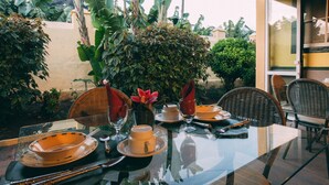 A dining table set with plates, glasses, and cutlery, surrounded by lush greenery and a view of a mountain. - Hotel Rural Casamarilla (Garachico)