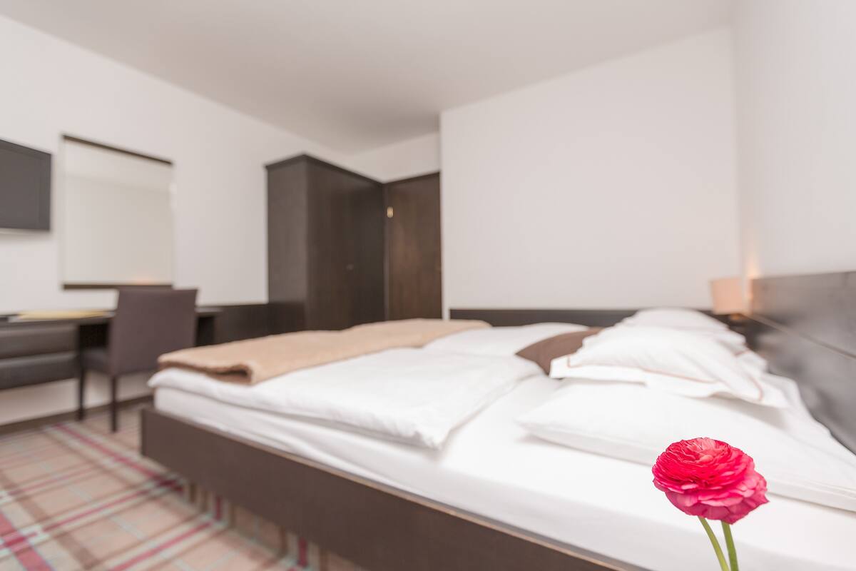Quarto de hotel moderno com cama, escrivaninha e cadeira.