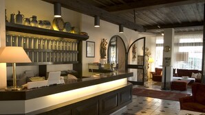 Un espace d’accueil comprenant un comptoir, une lampe, un miroir et un coin salon avec des canapés.