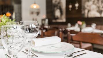 A dining table set with wine glasses, plates, and cutlery, with a blurred background of a restaurant interior.