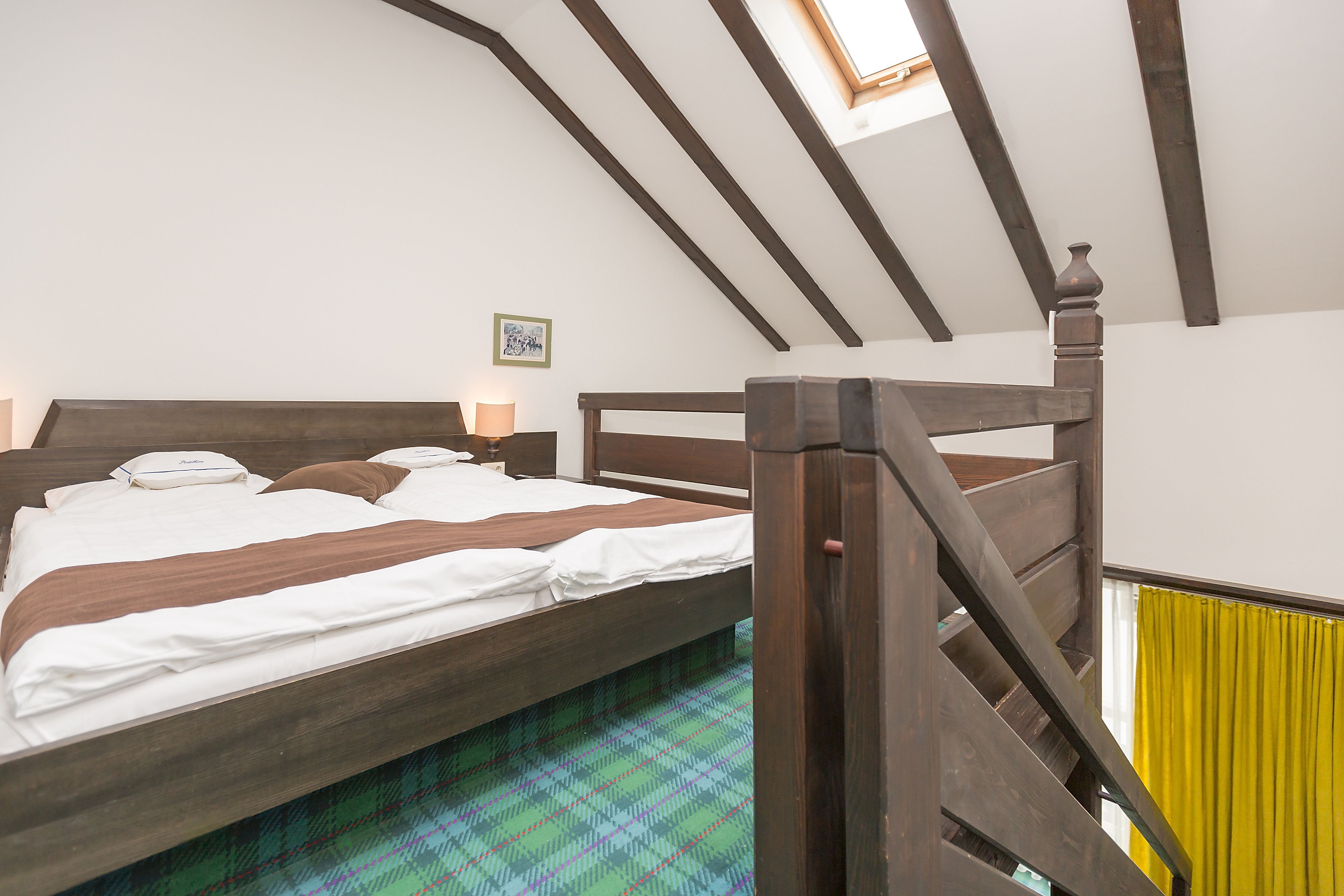 A bedroom with a wooden bed, a skylight, and a view of the outside.