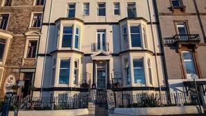 A multi-story building with a central entrance, bay windows, and a corner turret. - The Riviera Guest House (Whitby)