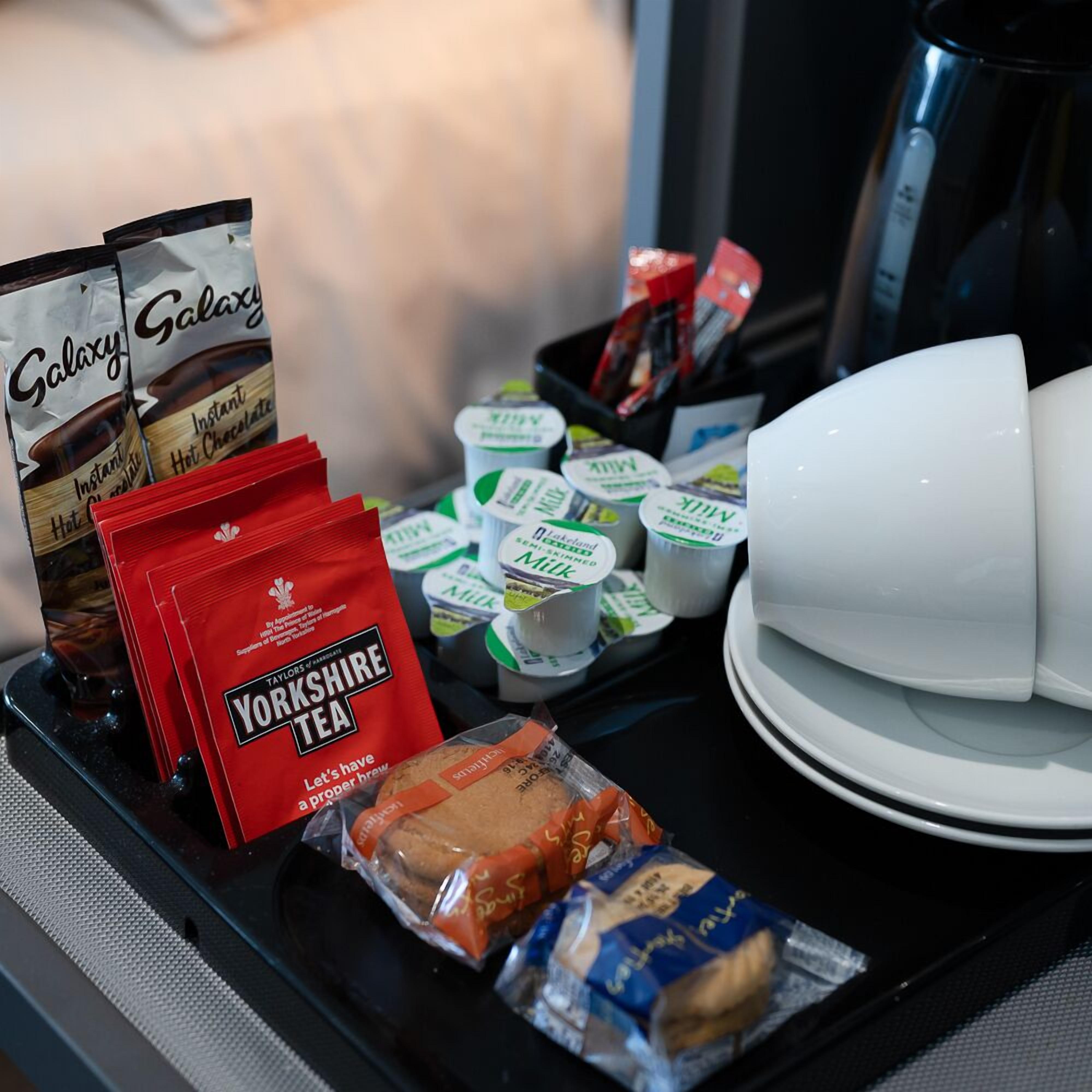 A breakfast tray with instant hot chocolate, Yorkshire tea, milk, yogurt, and croissants.