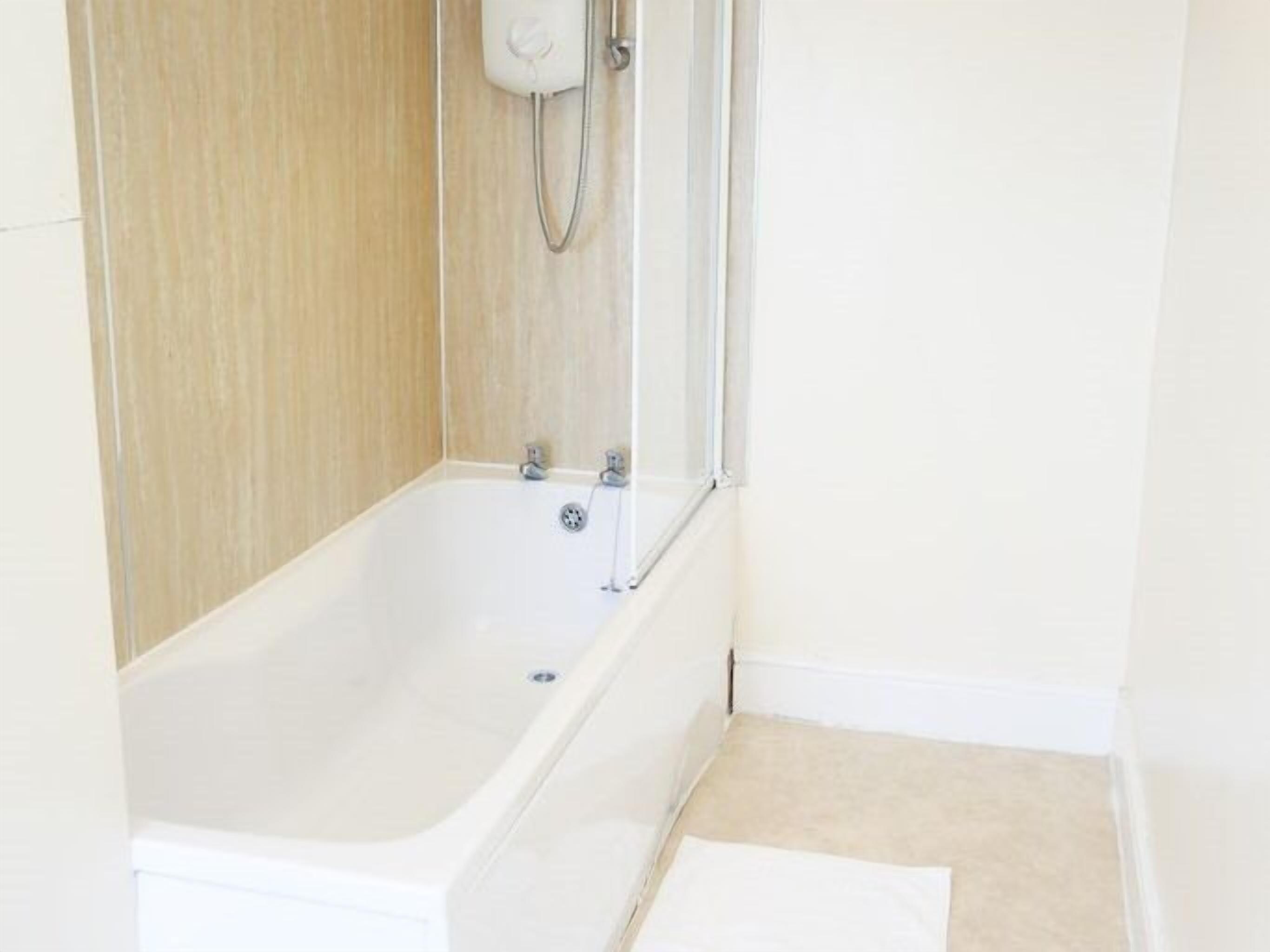 Ein Badezimmer mit einer weißen Badewanne, einer Dusche und einer Holzwand.