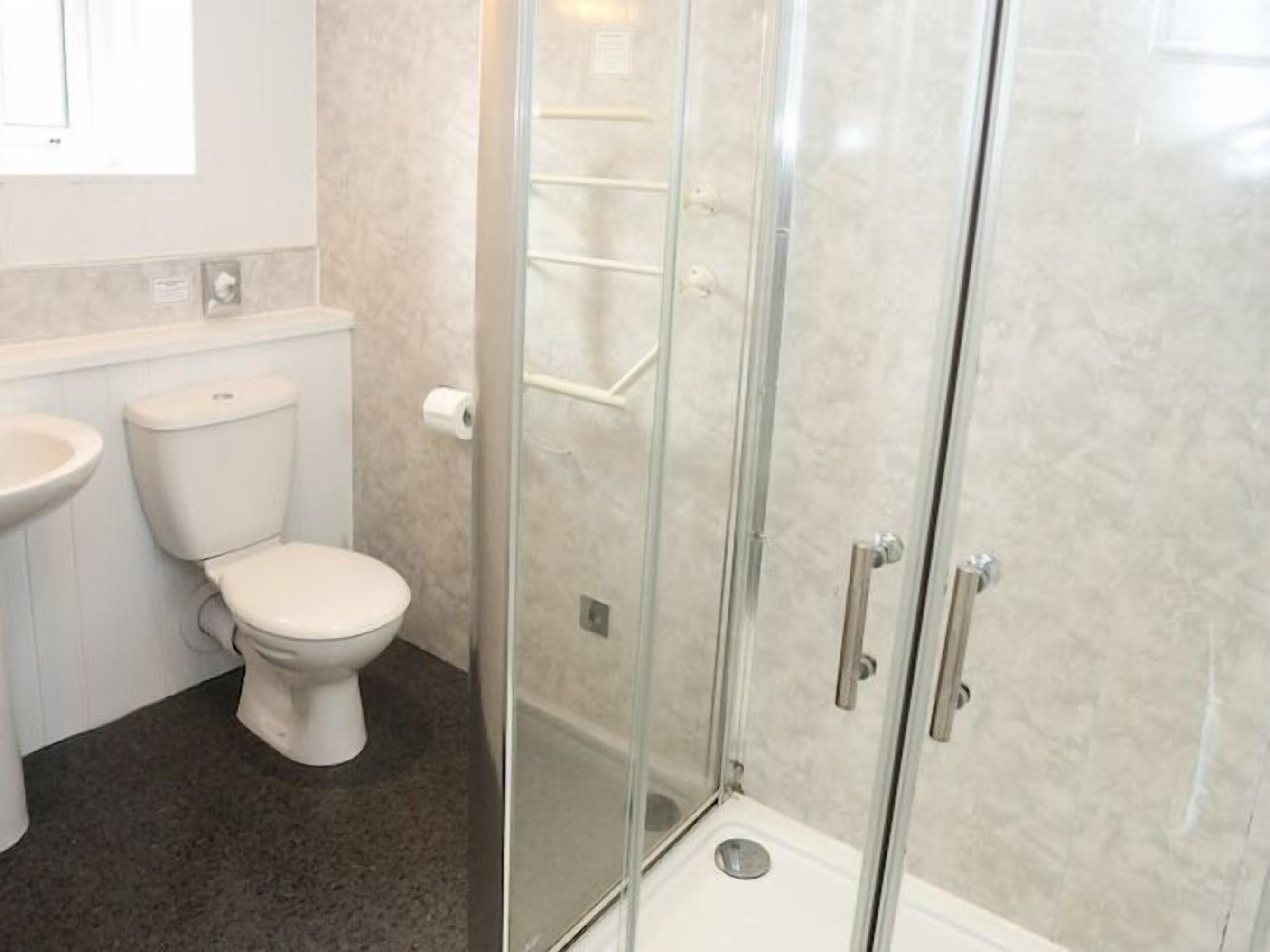 A bathroom with a toilet, sink, and a glass-enclosed shower stall.