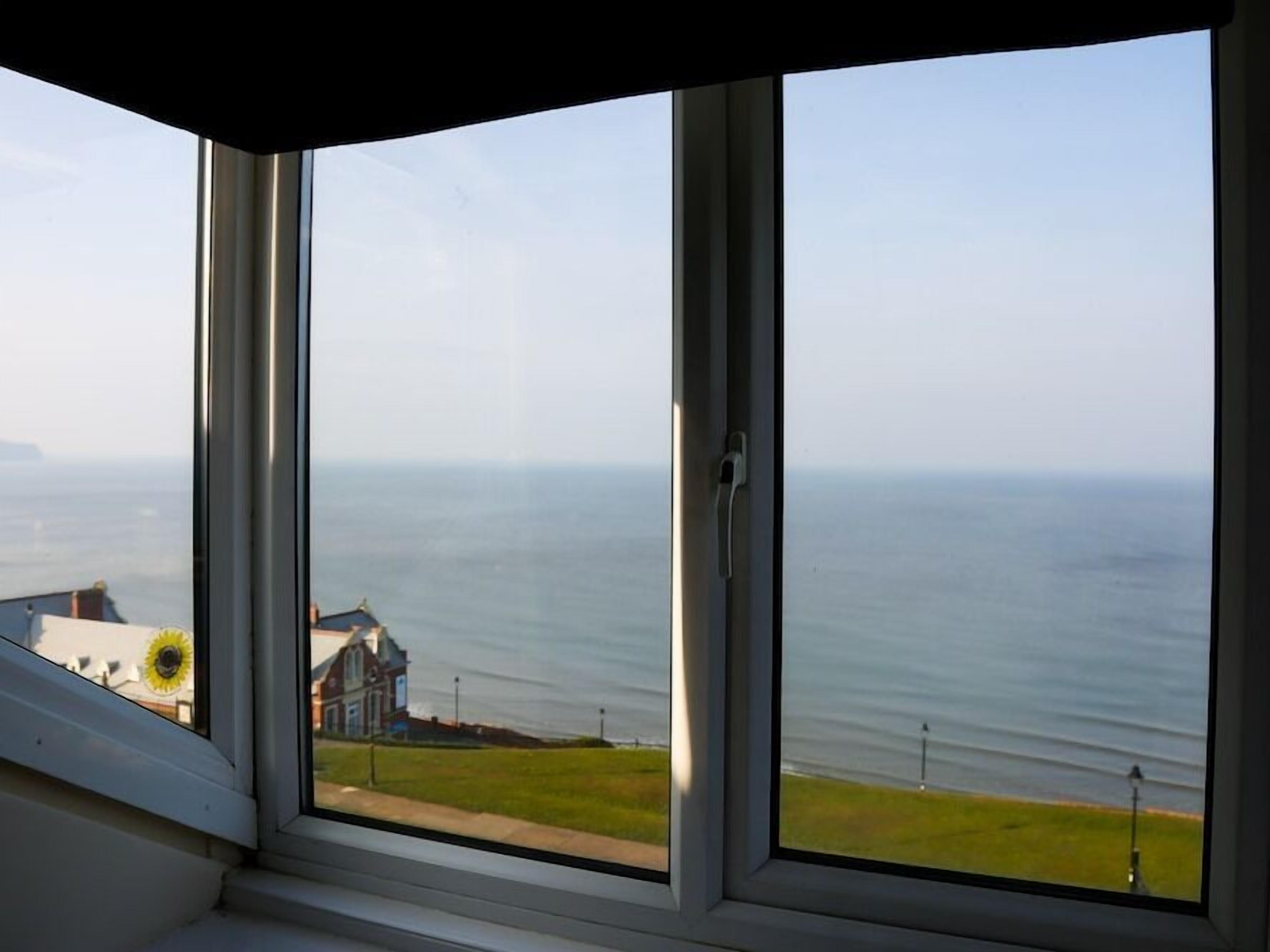 Ein Eckfenster mit Blick auf das Meer und ein Gebäude gegenüber.