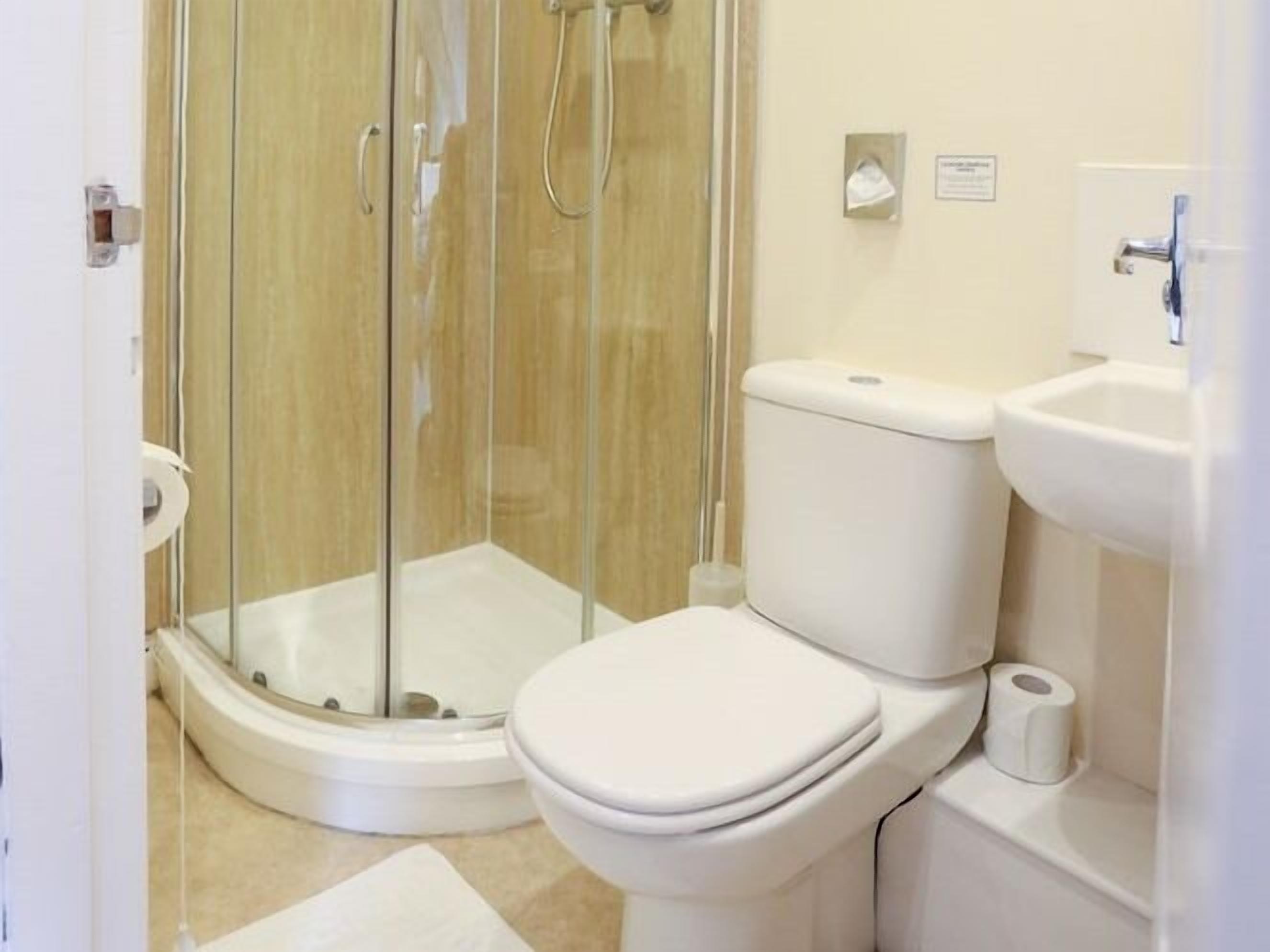 Une salle de bain avec une douche à parois de verre, des toilettes et un lavabo.