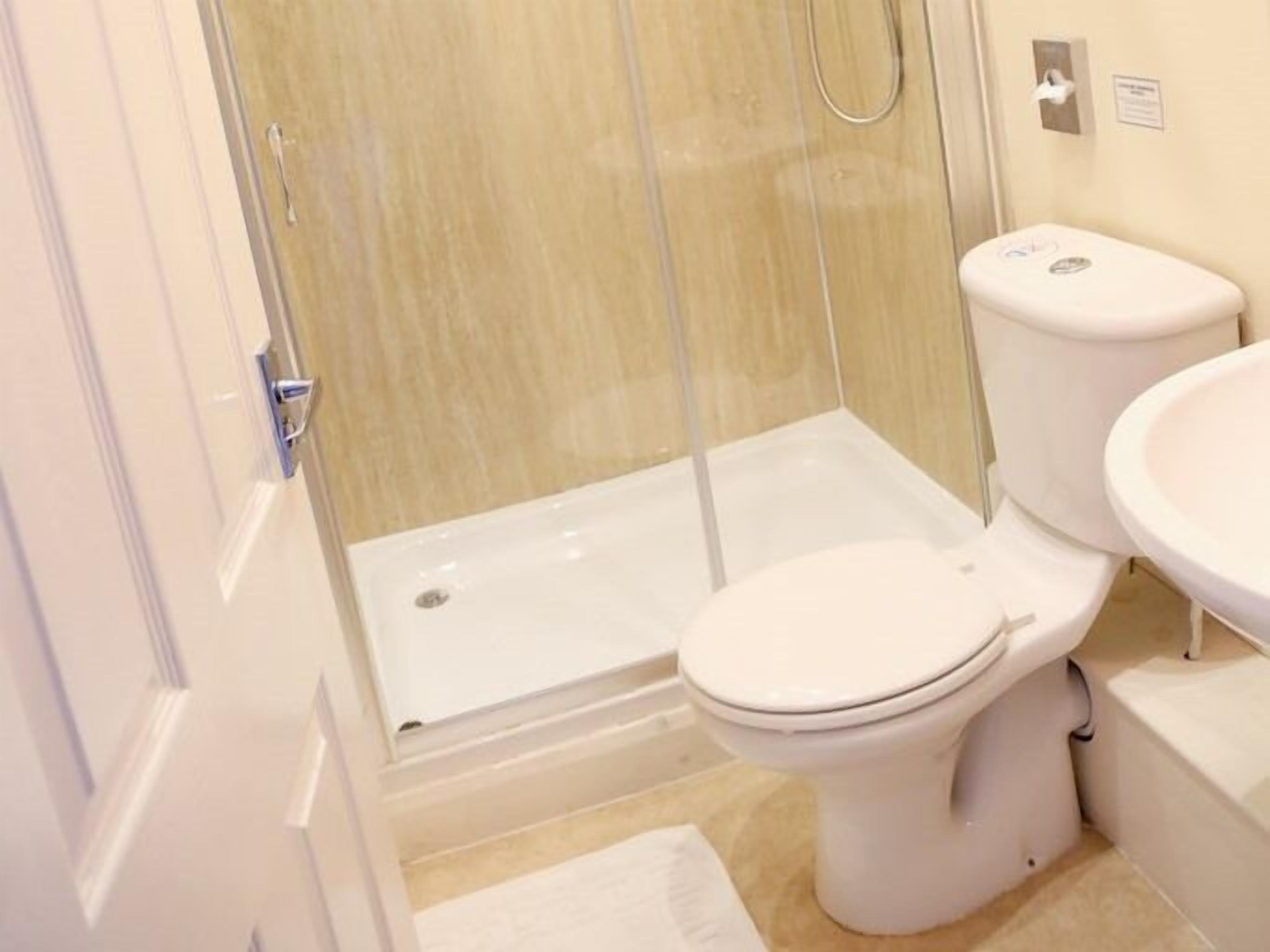 A bathroom with a glass-enclosed shower, a toilet, and a sink.