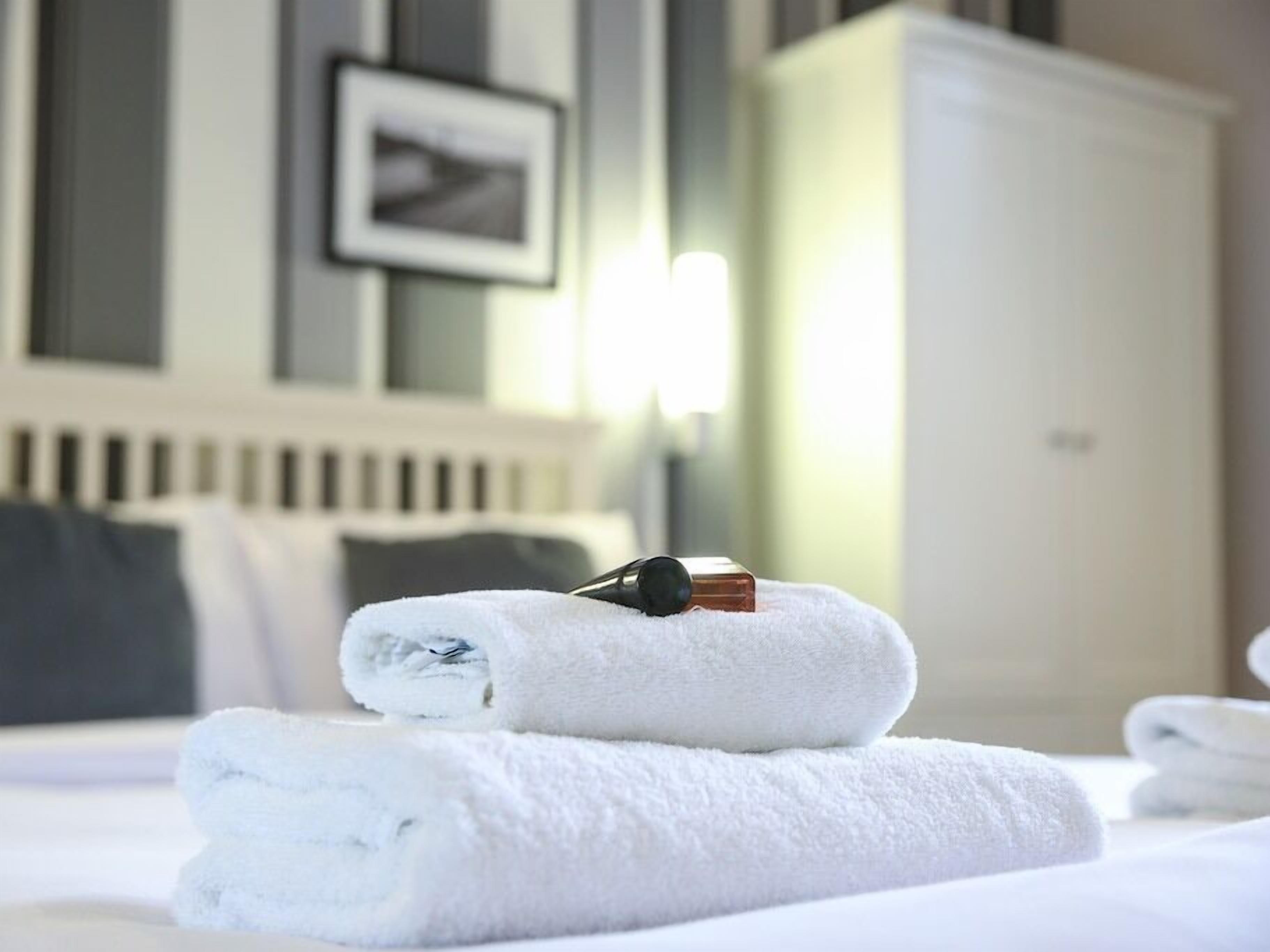 A neatly made bed with folded white towels and a pair of headphones on top.