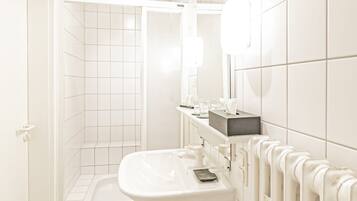Een moderne badkamer met een witte wastafel, spiegel en douche.