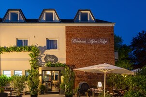 A building with a sign reading "Weinhaus Fischer Kapp" and outdoor seating with umbrellas.