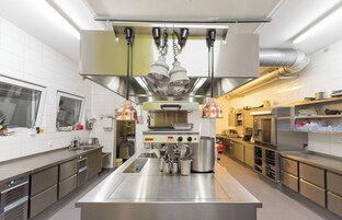 A modern commercial kitchen with stainless steel appliances, a central island, and overhead lighting.