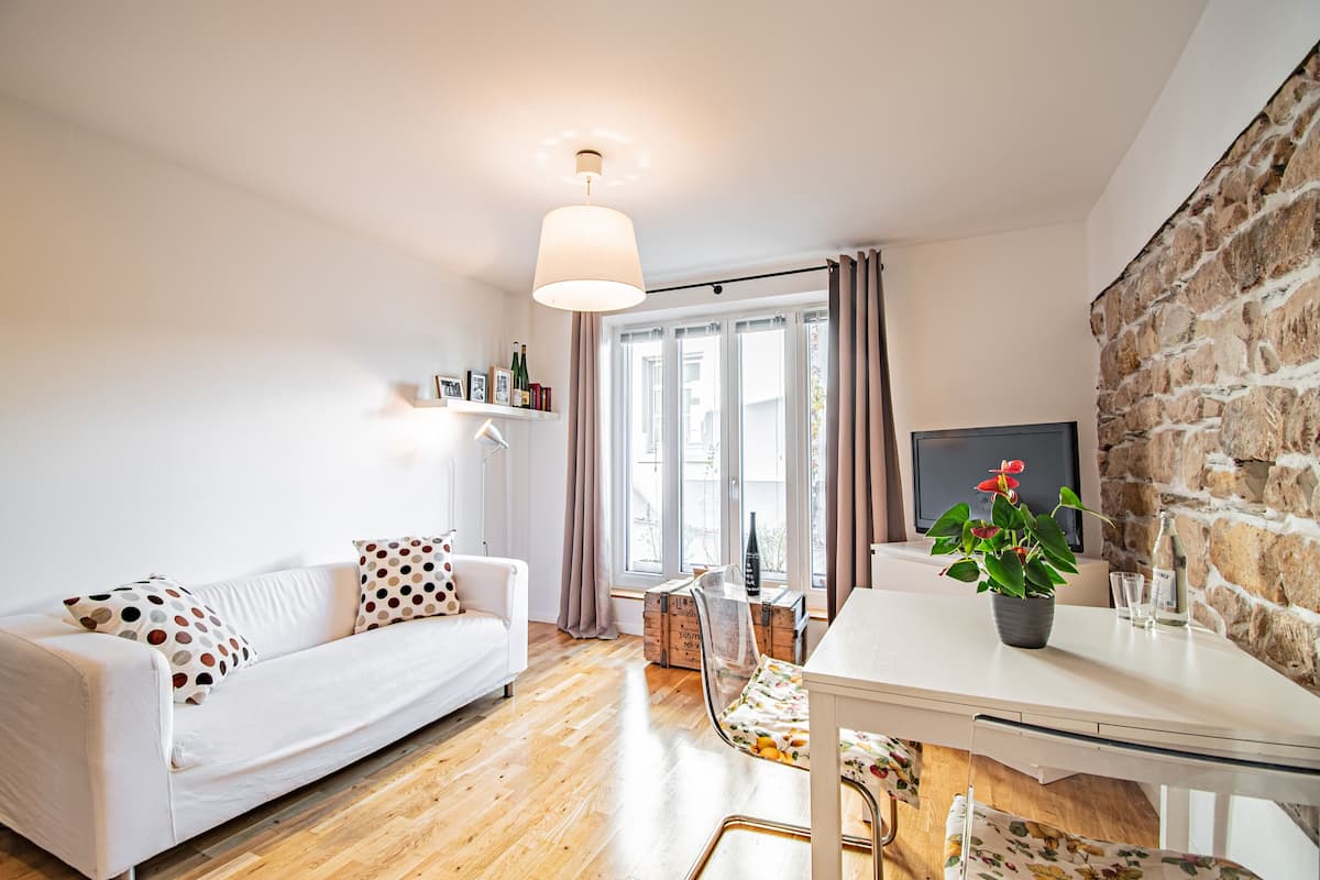 Una sala moderna con un sofá blanco, una mesa de comedor de vidrio y una pared de piedra.