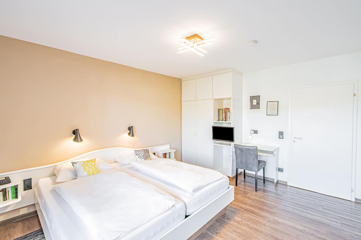 Un dormitorio moderno con cama, mesitas de noche, escritorio y una silla.