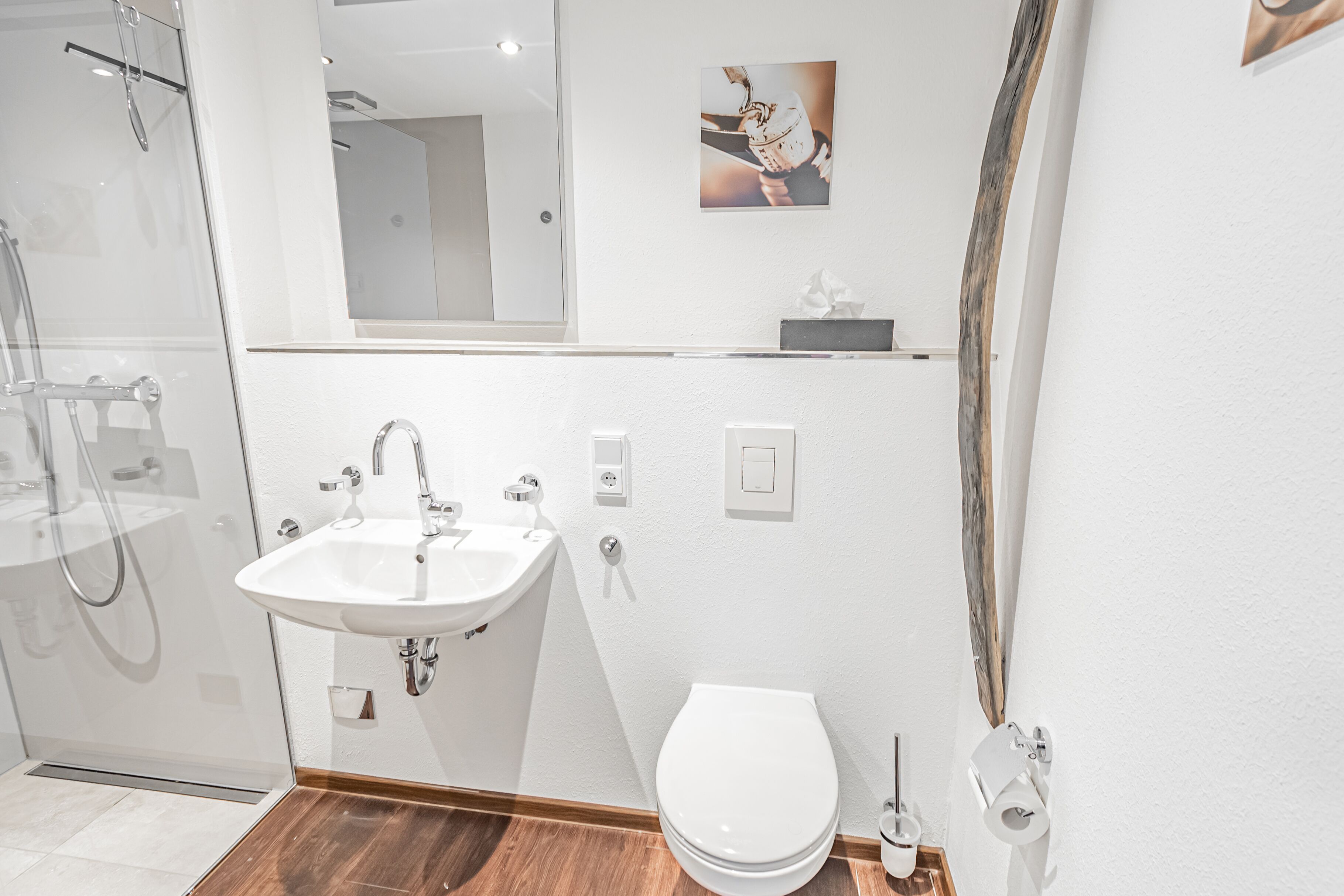 A modern bathroom with a white sink, a toilet, and a shower area.
