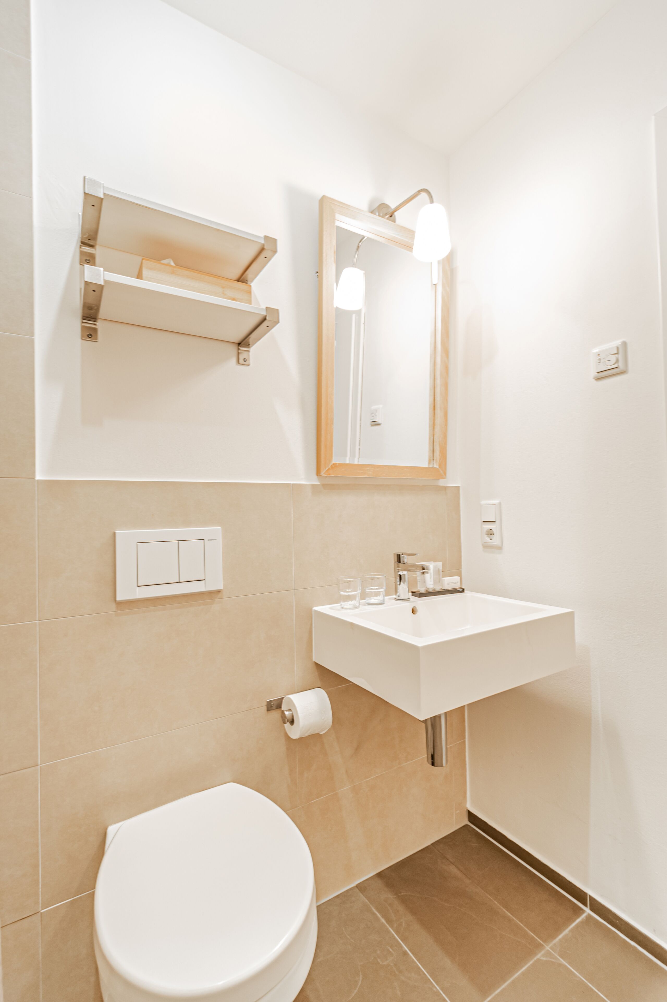 Une salle de bain avec des toilettes blanches, un lavabo avec un miroir au-dessus et un porte-serviettes.