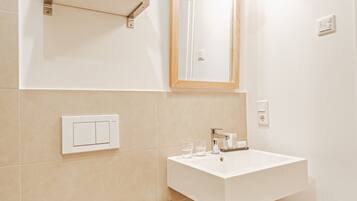 Une salle de bain avec des toilettes blanches, un lavabo avec un miroir au-dessus et un porte-serviettes.
