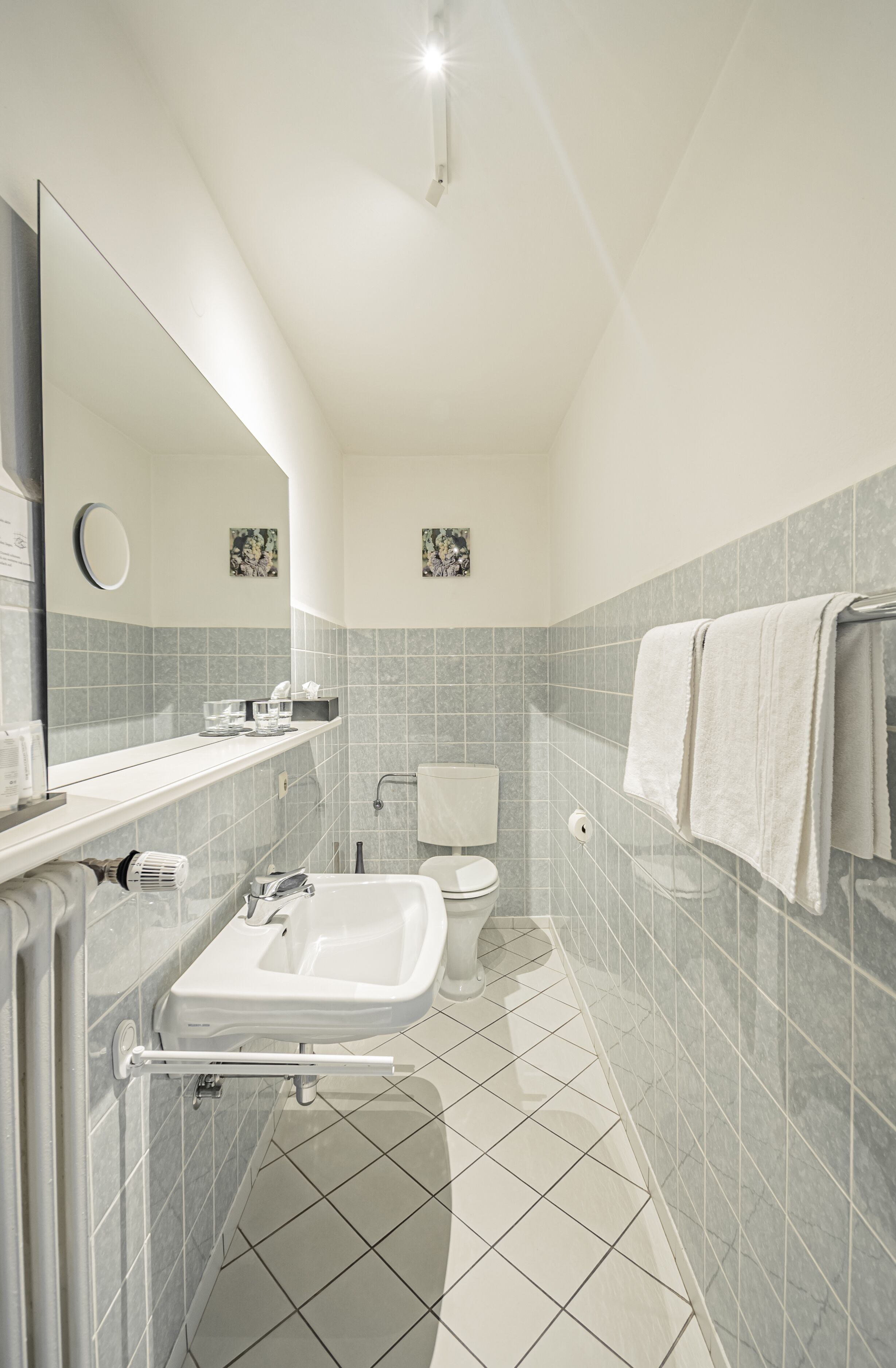 Une salle de bain moderne équipée d’un lavabo, d’un miroir, de toilettes et d’un porte-serviettes.