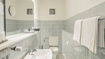 Une salle de bain moderne équipée d’un lavabo, d’un miroir, de toilettes et d’un porte-serviettes.