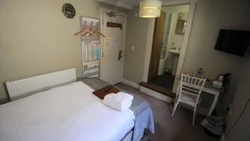 Una habitación de hotel con una cama, un escritorio con una silla, un espejo y una televisión.