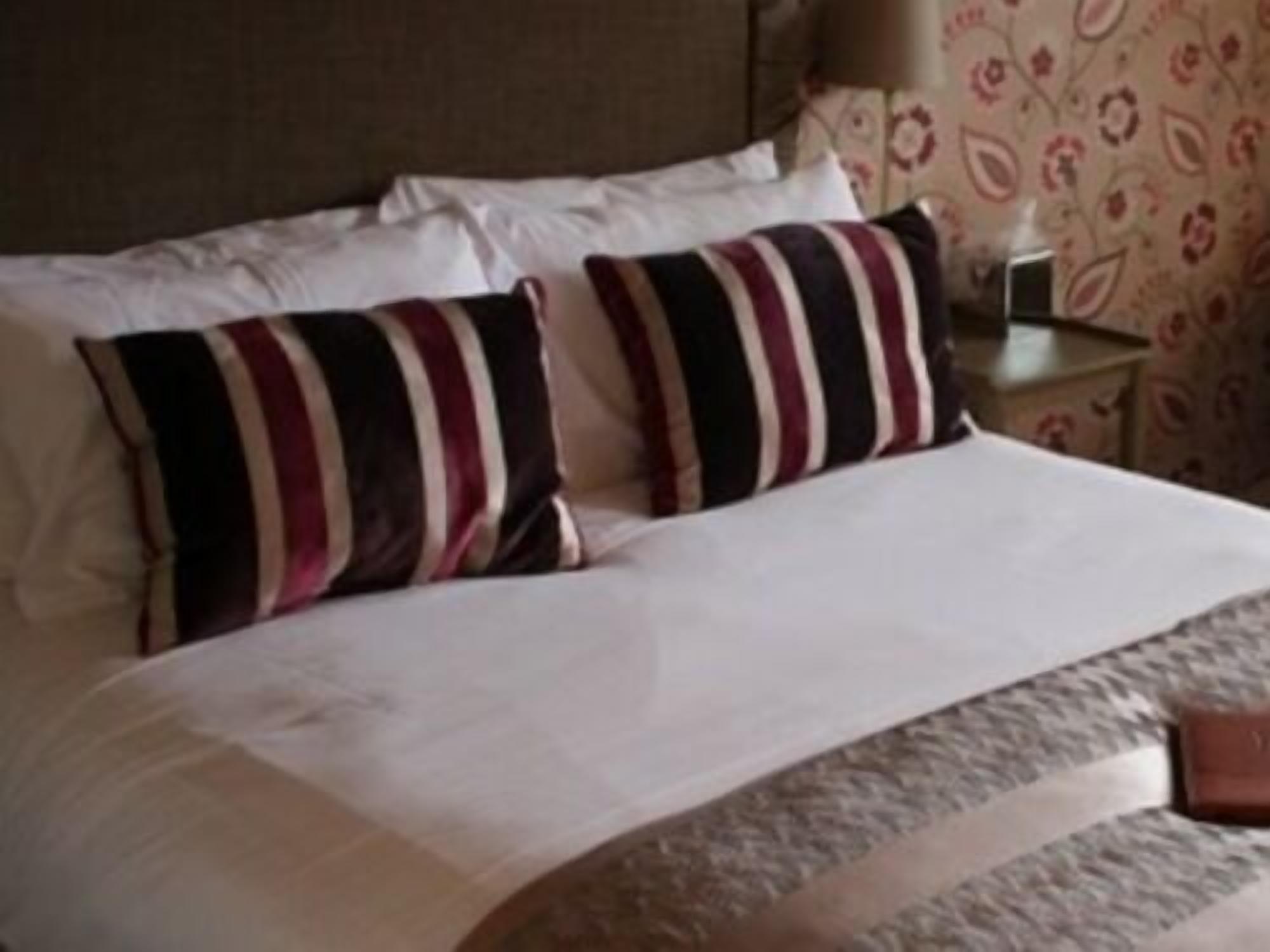 A neatly made bed with striped pillows and a white comforter.